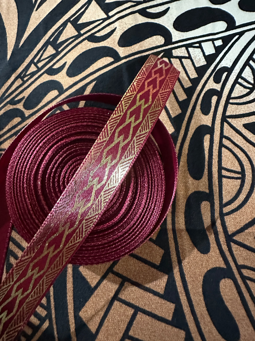 5/8” wide maroon satin ribbon with metallic gold tribal design