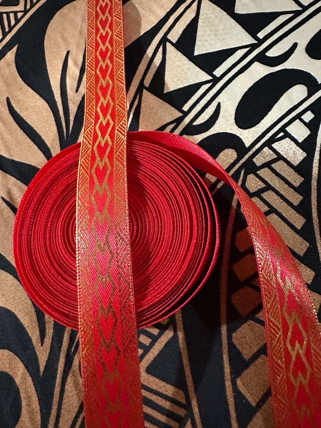 5/8” wide red satin ribbon with metallic gold tribal design